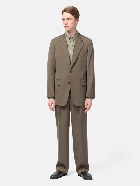 Model standing in studio wearing the AURALEE Light Wool Max Gabardine Jacket Dark in Olive Brown