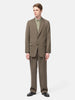 Model standing in studio wearing the AURALEE Light Wool Max Gabardine Jacket Dark in Olive Brown