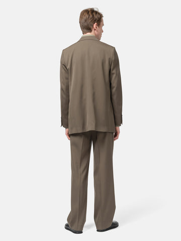 Rear View of the Model standing in studio wearing the AURALEE Light Wool Max Gabardine Jacket Dark in Olive Brown