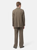 Rear View of the Model standing in studio wearing the AURALEE Light Wool Max Gabardine Jacket Dark in Olive Brown