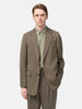 Half-body shot of the Model standing in studio wearing the AURALEE Light Wool Max Gabardine Jacket Dark in Olive Brown