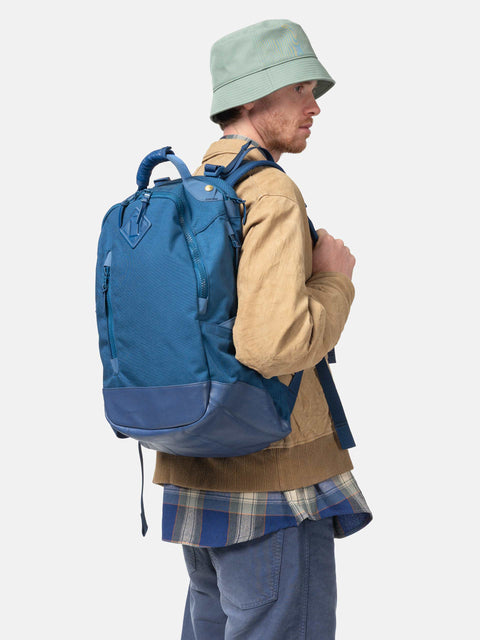 Model wearing the Visvim Cordura 20L backpack in Blue on the shoulder.
