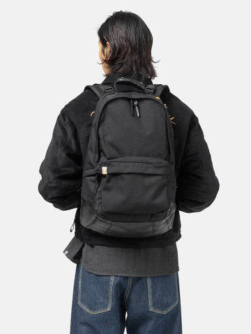 Model wearing the Visvim Cordura 22L backpack in black on the shoulder.