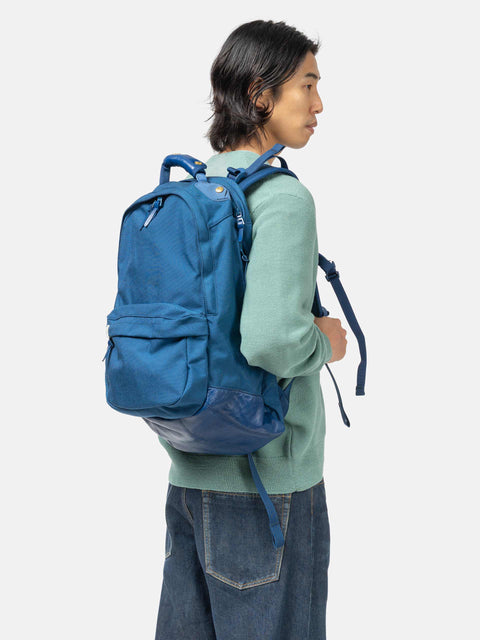 Model wearing the Visvim Cordura 22L backpack in BLue on the shoulder.