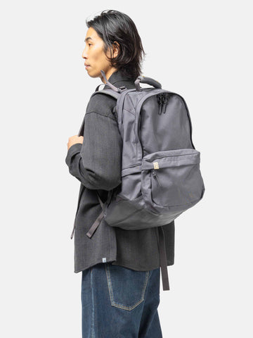 Model wearing the Visvim Cordura 22L backpack in Charcoal on the shoulder.
